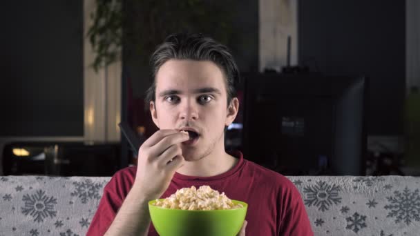 Young Guy Red Shirt Sits Couch Watches Eats Popcorn Watches — Αρχείο Βίντεο