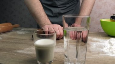 Genç aşçı zencefilli ekmek hamuru yoğurur. Masanın üzerinde bir bardak süt, su, merdane ve yeşil bir kap var. Pişirme kavramı