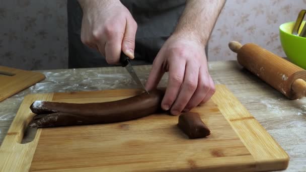 年轻厨师在木板上把生姜面团切成块 附近有一个滚动销和一个绿色容器 烘焙概念 — 图库视频影像