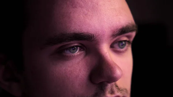 Karanlıkta oturup televizyon izleyen genç bir adamın yakın çekimi. Rahatlama ve hafta sonu konsepti