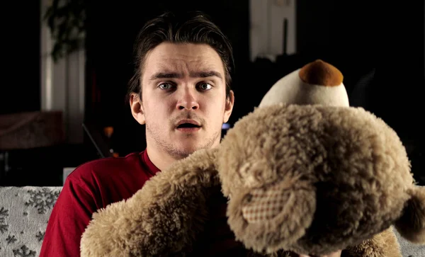 Kırmızı tişörtlü genç bir adam beyaz bir battaniyenin olduğu kanepede oturur ve televizyon izler ve korkudan bir oyuncak ayının arkasına saklanır. Hafta sonu ve rahatlama kavramı