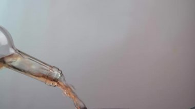 Cam bir şişeden dökülen gül şarabının yakın çekimi. Beyaz arka planda izole edilmiş şarap şişesi. Alkol kavramı