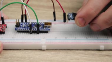 Working with electronics microcircuits on a breadboard, the hand of a white man arranges microcircuits, the concept of working with electrical modules and programming