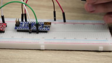 Working with electronics microcircuits on a breadboard, the hand of a white man arranges microcircuits, the concept of working with electrical modules and programming
