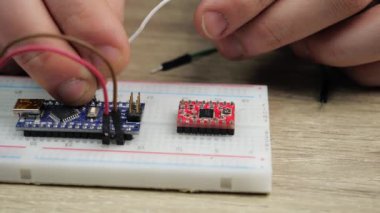 Working with electronics microcircuits on a breadboard, the hand of a white man arranges microcircuits, the concept of working with electrical modules and programming