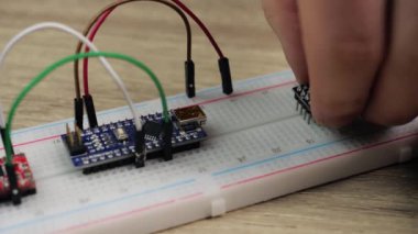 Working with electronics microcircuits on a breadboard, the hand of a white man arranges microcircuits, the concept of working with electrical modules and programming