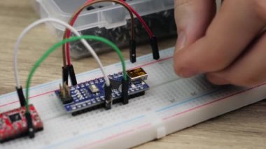 Working with electronics microcircuits on a breadboard, the hand of a white man arranges microcircuits, the concept of working with electrical modules and programming