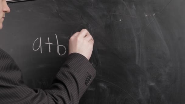 黒いスーツの先生は黒板にチョークで数式を書きます 学校概念 — ストック動画