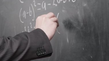 Siyah takım elbiseli erkek elleri yakın plan, öğretmen siyah karatahtaya matematik denklemleri yazıyor. Okul kavramı