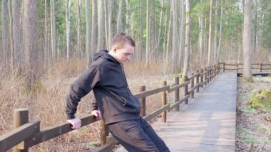 Siyah eşofmanlı adam köprünün parmaklıklarından şınav çekiyor. Sağlıklı yaşam tarzı kavramı