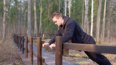 Siyah eşofmanlı adam köprünün parmaklıklarından şınav çekiyor. Sağlıklı yaşam tarzı kavramı