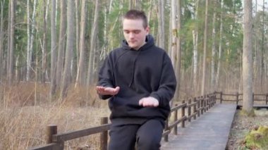 Siyah eşofmanlı bir adam dizlerine ve ellerine dokunarak koşuyor. Kahverengi köprüde. Sağlıklı yaşam tarzı kavramı