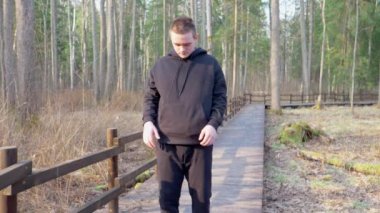 Siyah eşofmanlı adam ellerini bacaklarına uzatarak esneme egzersizleri yapıyor. Sağlıklı yaşam tarzı kavramı