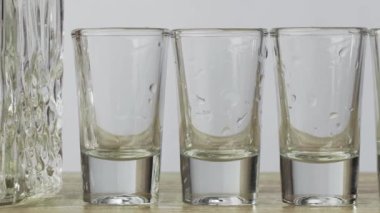 Tahta bir masanın üzerinde sıvı ve boş bardaklarla bir sürahide yakın çekim, ve sonuncusu da bir adamın elinin içtiği alkol. Alkol ve rahatlama kavramı