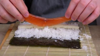 Genç aşçı farklı ürünlerden rulo yapmayı öğreniyor, evde suşi ve suşi yapıyor, Japon yemeği kavramı.