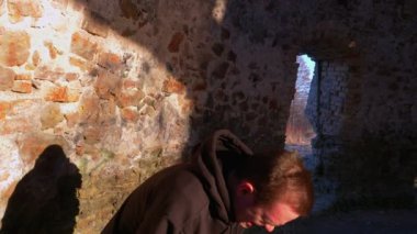 Sokakta siyah eşofmanlı genç adam, Grieves güneşe doğru bakıyor, eski bir değirmenin içinde, spor hayatı konseptinde.