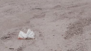 Eski yırtık kitabın yattığı kirli toprak, doğayı kirletme kavramı, ekolojik felaket.