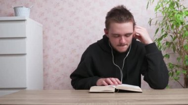 Genç adam kulaklıkla müzik dinliyor ve okuyor, siyah eşofman giyiyor, gençlerin konsepti....