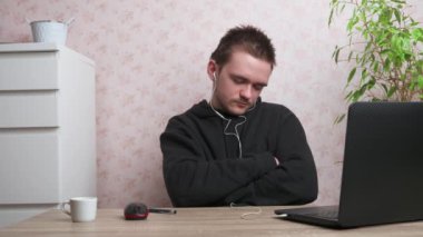 Genç adam bilgisayarda oturur ve uyur, masaya oturur, gençlik kavramı.