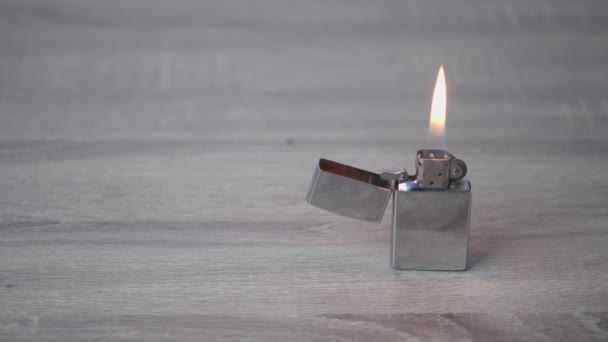金属鉄ガソリンライター燃焼し 軽い木製のテーブルの上に立つ 火災抽出コンセプト — ストック動画