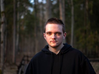 Siyah eşofmanlı bir adam, orman arka planında bir portre, gün batımında güneş, adam spora gider, sağlıklı yaşam tarzı kavramı..