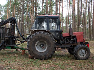 Kesilen ağaçları toplayan traktör yan duruyor, ağaç kesme konsepti, ormanların tahrip edilmesi..