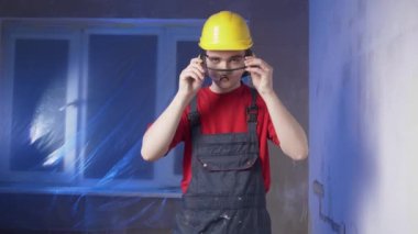 İnşaatçı koruyucu aksesuarlar takıyor, inşaat kıyafetleri giyiyor ve başlık takıyor, duvarları delecek, inşaat konsepti, elektrik döşemesi...