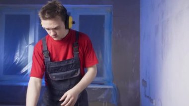 İnşaatçı koruyucu aksesuarlar takıyor, inşaat kıyafetleri giyiyor ve başlık takıyor, duvarları delecek, inşaat konsepti, elektrik döşemesi...