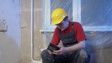 İnşaatçı işten çok yorgun olduğu için dinlenmek için oturdu. İnşaat kıyafetleri ve kask giyiyordu. Duvarları, inşaat konseptini, elektrik döşemesini delecekti.