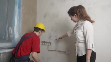 Müşteri inşaatçının performansını kontrol eder, işçi bir şeyi ölçer, inşaat konsepti, elektrik döşemesi