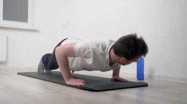 Genç bir atletik adam siyah bir paspas üzerinde egzersiz yapıyor, vücut ve zihni güçlendirmek için egzersiz yapıyor. Ev ödevi konsepti, yoga