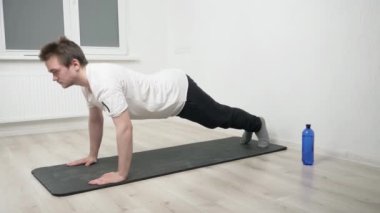 Genç bir atletik adam siyah bir paspas üzerinde egzersiz yapıyor, vücut ve zihni güçlendirmek için egzersiz yapıyor. Ev ödevi konsepti, yoga