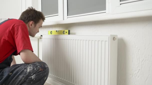 Loodgieter Installeert Een Witte Metalen Radiator Aan Centrale Verwarmingsbuizen Kamer — Stockvideo