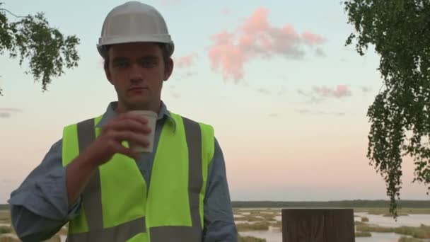 Ung Ekolog Byggare Trött Att Dricka Kaffe Och Titta Kameran — Stockvideo