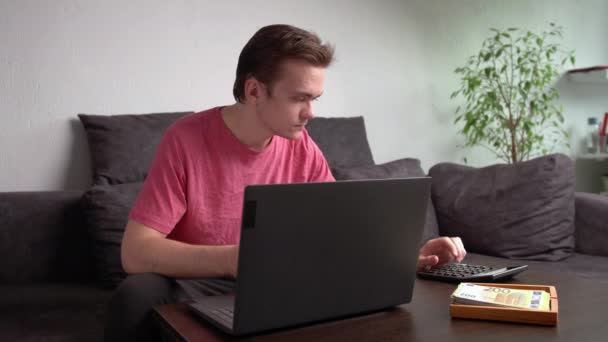 Jovem Sentado Sofá Mesa Com Laptop Contando Dinheiro Para Despesas — Vídeo de Stock