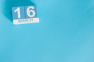 16 Mart. Mavi arka plan üzerinde 16 Mart ahşap renkli takvim görüntüsü. Bahar günü, metin için boş alan