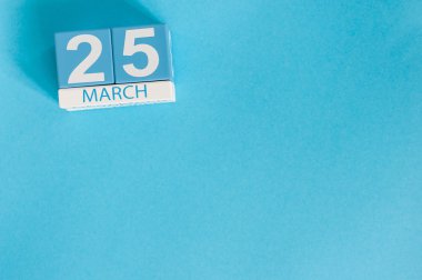 25 Mart. Mavi arka plan üzerinde 25 Mart ahşap renkli takvim görüntüsü. Bahar günü, metin için boş alan.