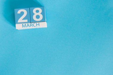 28 Mart. Mavi arka plan üzerinde 28 Mart ahşap renkli takvim görüntüsü. Bahar günü, metin için boş alan