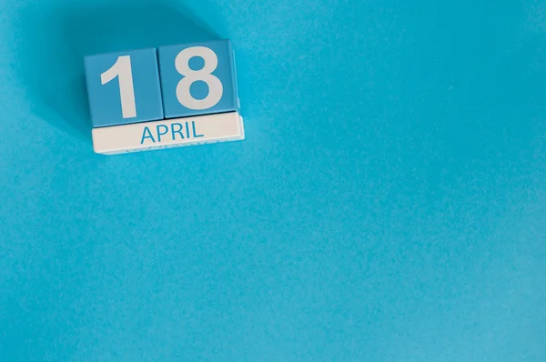 18. April. Bild vom 18. April Holzfarbkalender auf blauem Hintergrund. Frühlingstag, leerer Raum für Text. Internationaler Tag für Denkmäler und Amateurfunk — Stockfoto