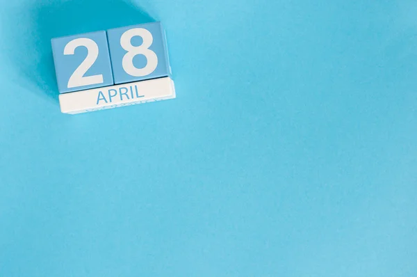 Le 28 avril. Jour de l'impôt. Image du 28 avril calendrier de couleurs en bois sur fond bleu. Printemps, espace vide pour le texte — Photo