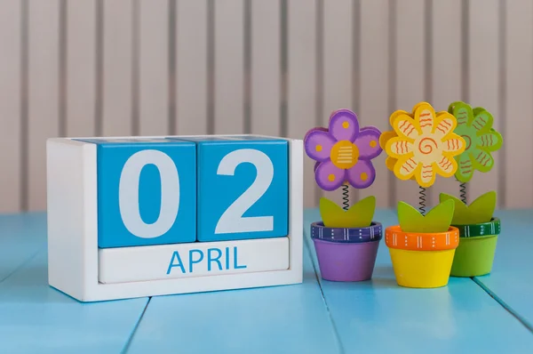 Il 2 aprile. Immagine di 2 aprile calendario a colori in legno su sfondo bianco con fiori. Giorno di primavera, spazio vuoto per il testo. Giornata internazionale del libro per bambini — Foto Stock