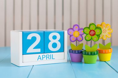 April 28th. Tax Day. Image of april 28 wooden color calendar on white background with flowers. Spring day, empty space for text