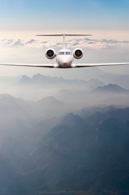Bulutlar ve günbatımı dağda Alpler üzerinden uçak fly. Bir büyük yolcu ve yük uçak, iş jeti, havayolu önden görünümü. Ulaşım, seyahat kavramı