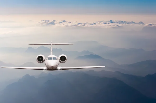 Airplane fly over clouds and Alps mountain on sunset. Front view of a big passenger or cargo aircraft, business jet, airline. Transportation, travel concept