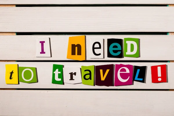 I need to travel - written with color magazine letter clippings on wooden board. Summer vacation concept — Stock Photo, Image