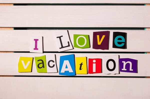 I love vacation - written with color magazine letter clippings on wooden board. Travel concept image — Stock Photo, Image