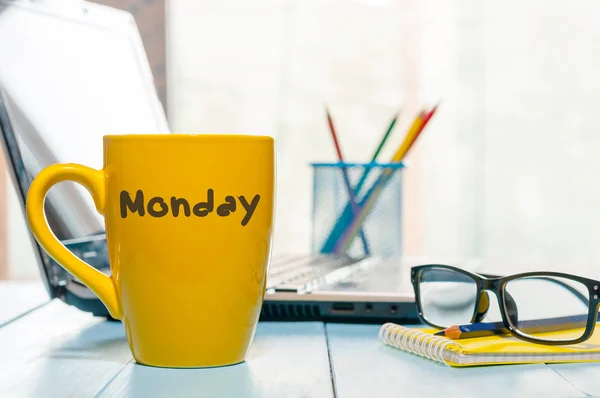 Monday written on yellow coffee or tea cup at wooden boards table, workplace, office sunlight morning background — Stock Photo, Image