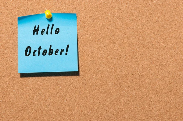 Hello October message on the blue sticker pinned at notice cork board. Autumn concept. With empty space for text