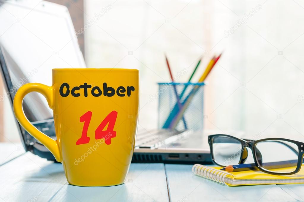 October 14th. Day 14 of month, morning coffee at yellow cup with calendar on auditor workplace background. Autumn time. Empty space for text