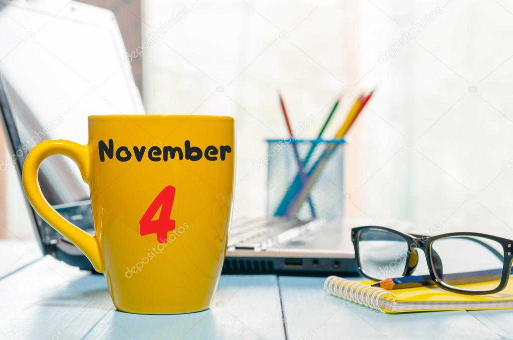 November 4th. Day 4 of month, calendar on yellow cup with yea or coffee, student workplace background. Autumn time
